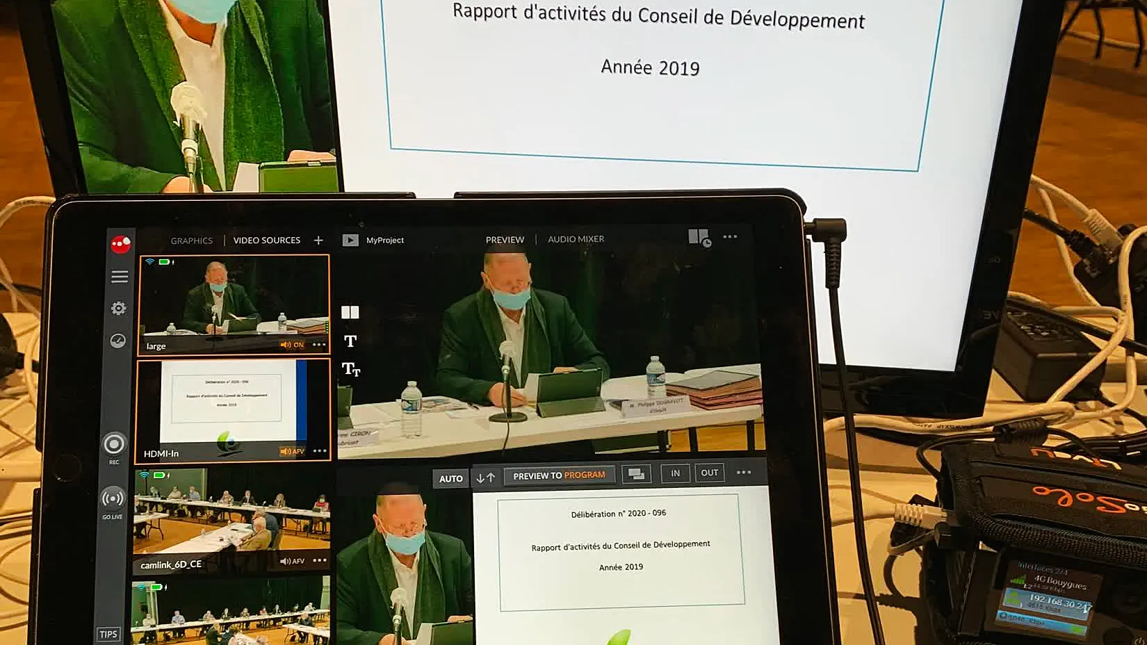 La régie installée devant l'écran où est projetée une délibération : tablette de réalisation et console son